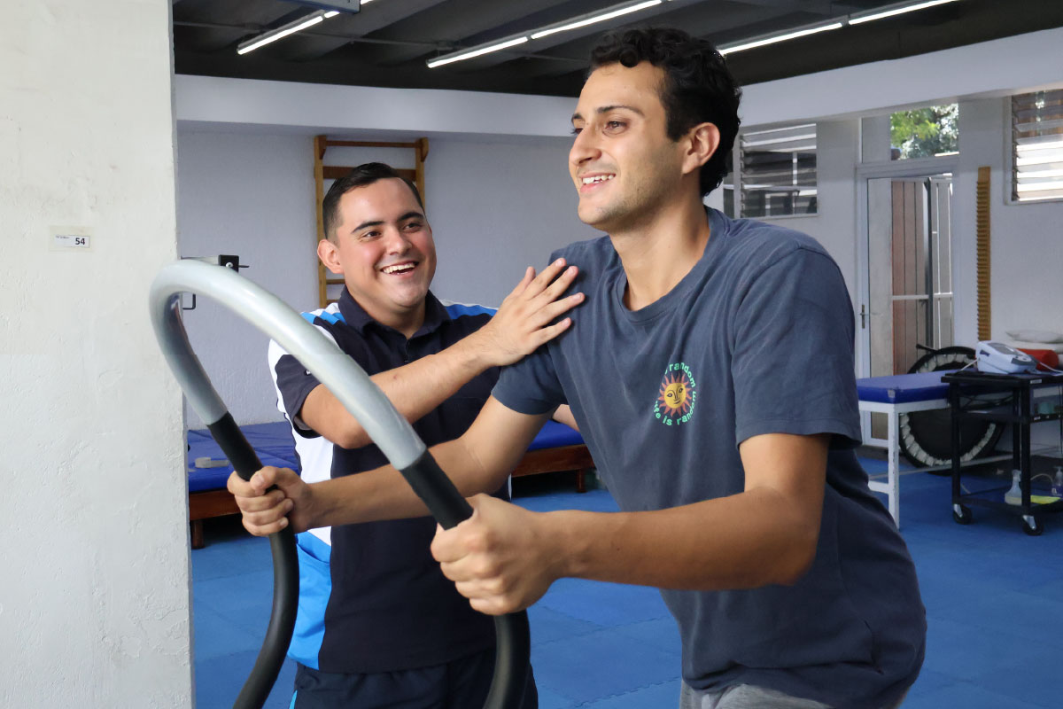 estudiante de fisioterapia guía a un paciente durante una sesión de ejercicios con equipo de rehabilitación en un área clínica