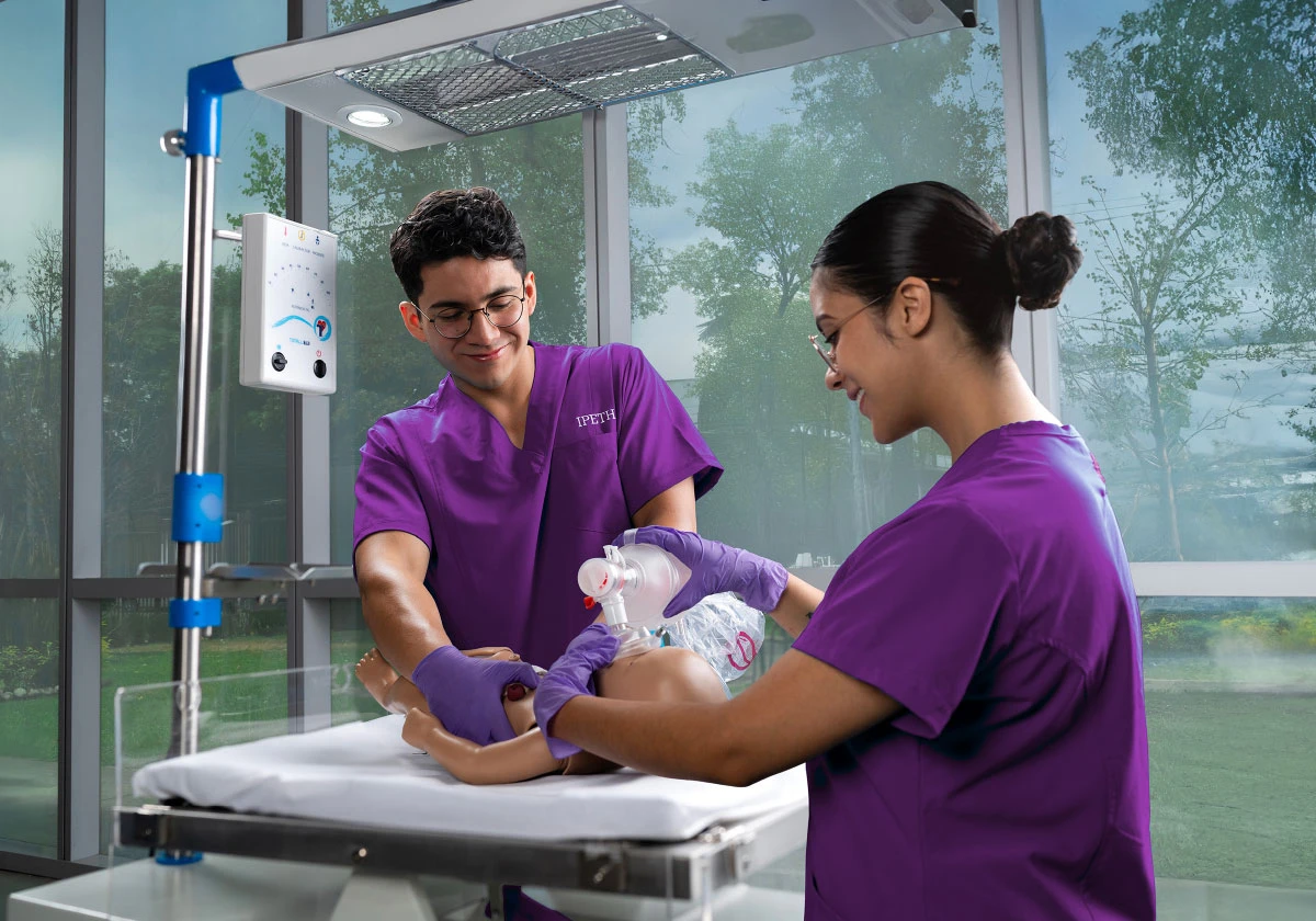 dos estudiantes de la licenciatura en enfermería de ipeth realizan práctica de reanimación neonatal en un laboratorio de simulación, utilizando un maniquí bebé y equipo clínico especializado